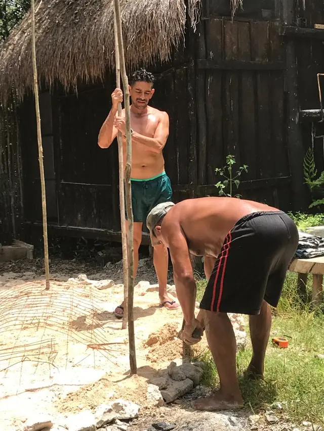 Dos personas clavando las varas y armando el cimiento del temazcal