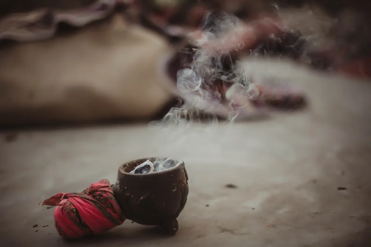 Copal humeando en un cuenco de barro, con la luz filtrada entre las hojas