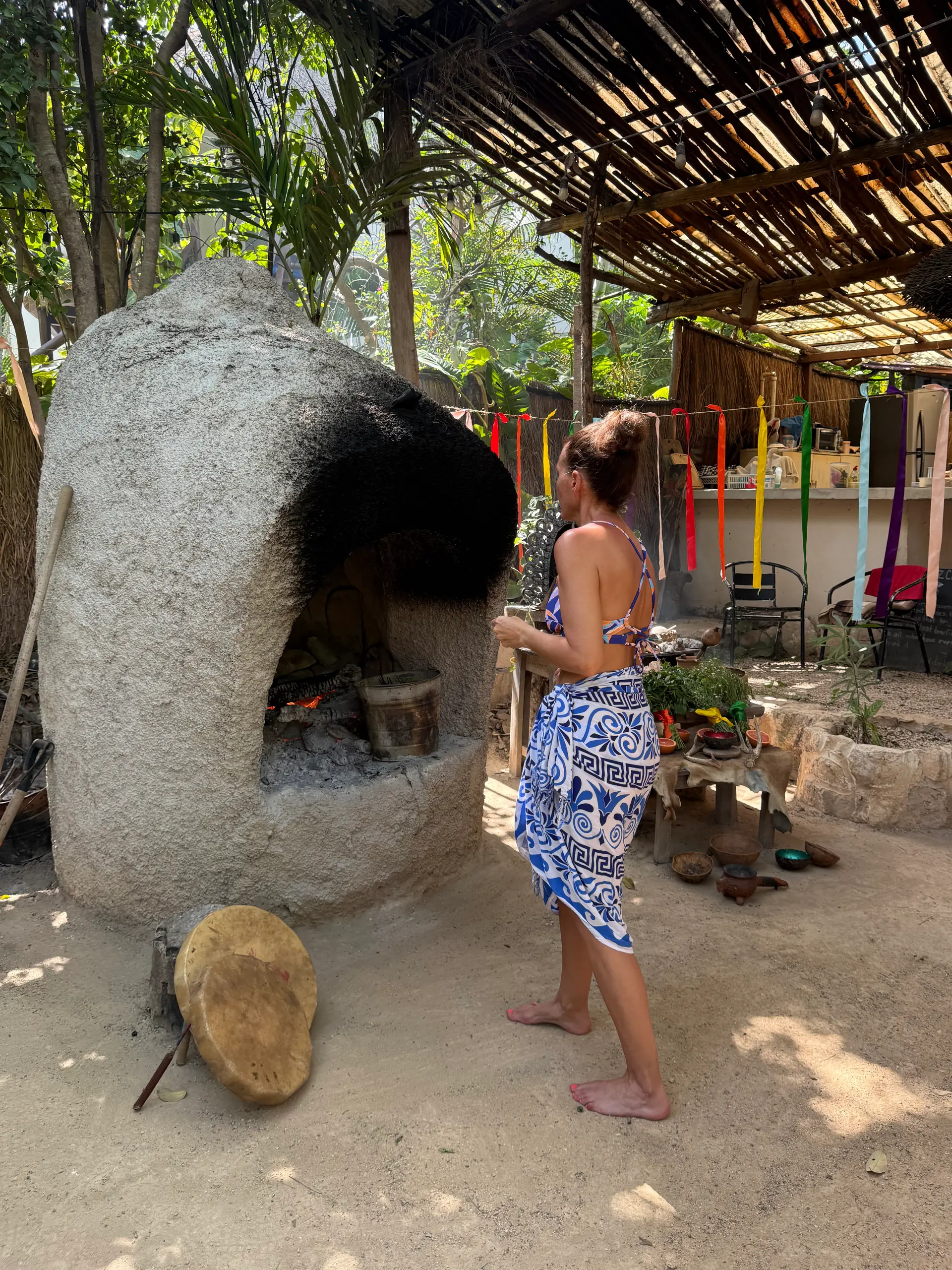 Horno de piedra encendido, con los listones de colores de los siete chakras colgando al lado