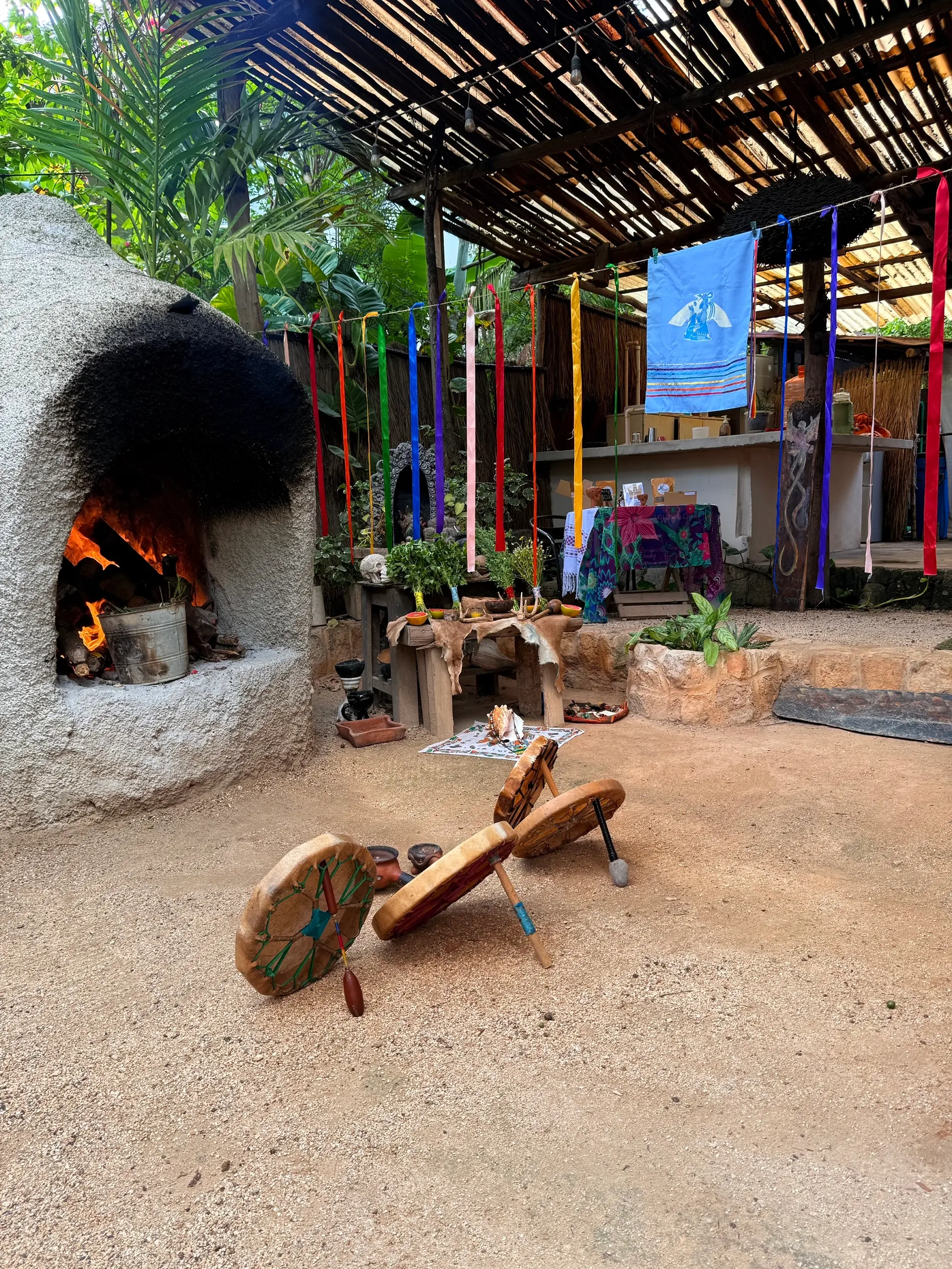 El horno de piedra encendido, con los listones de los siete colores a los lados y los tambores en el suelo