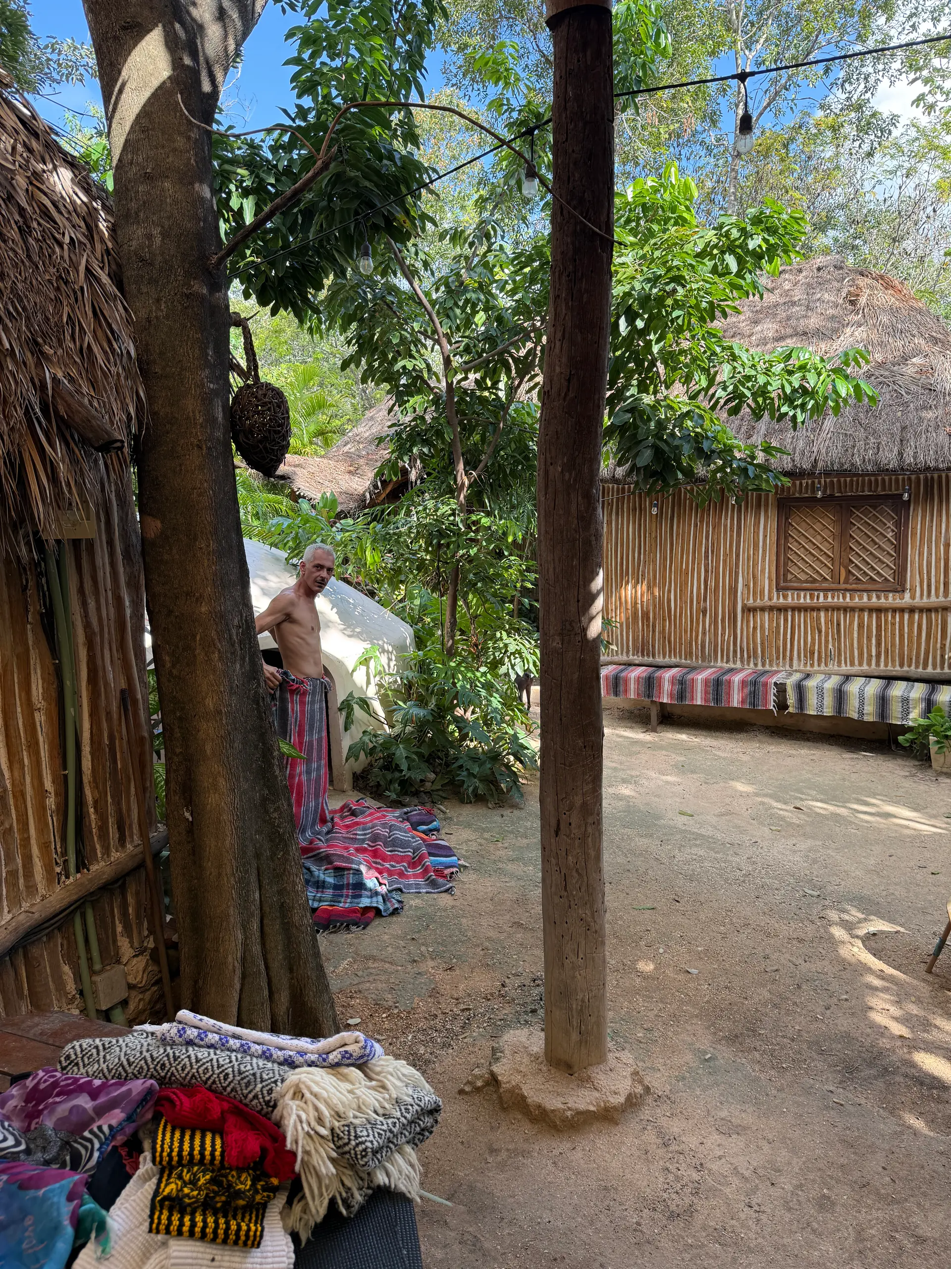 Textiles bordados apilados bajo la palapa, listos para el círculo
