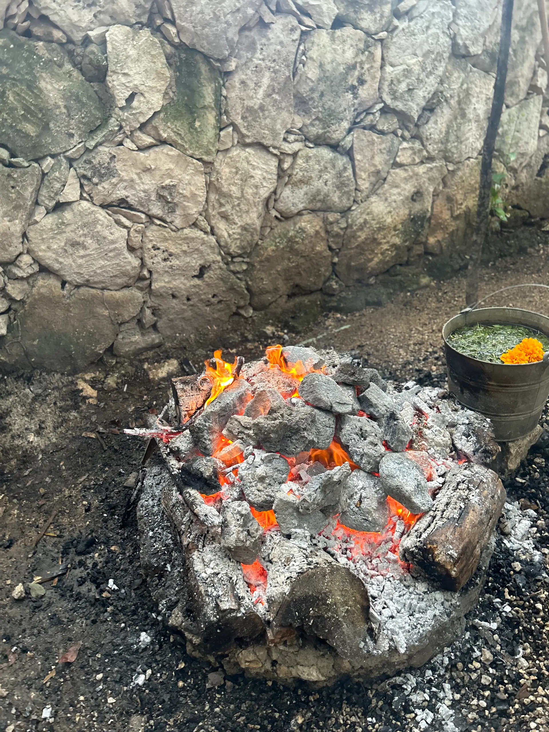 Las piedras volcánicas al rojo vivo en el fogón, junto a la olla de hierbas