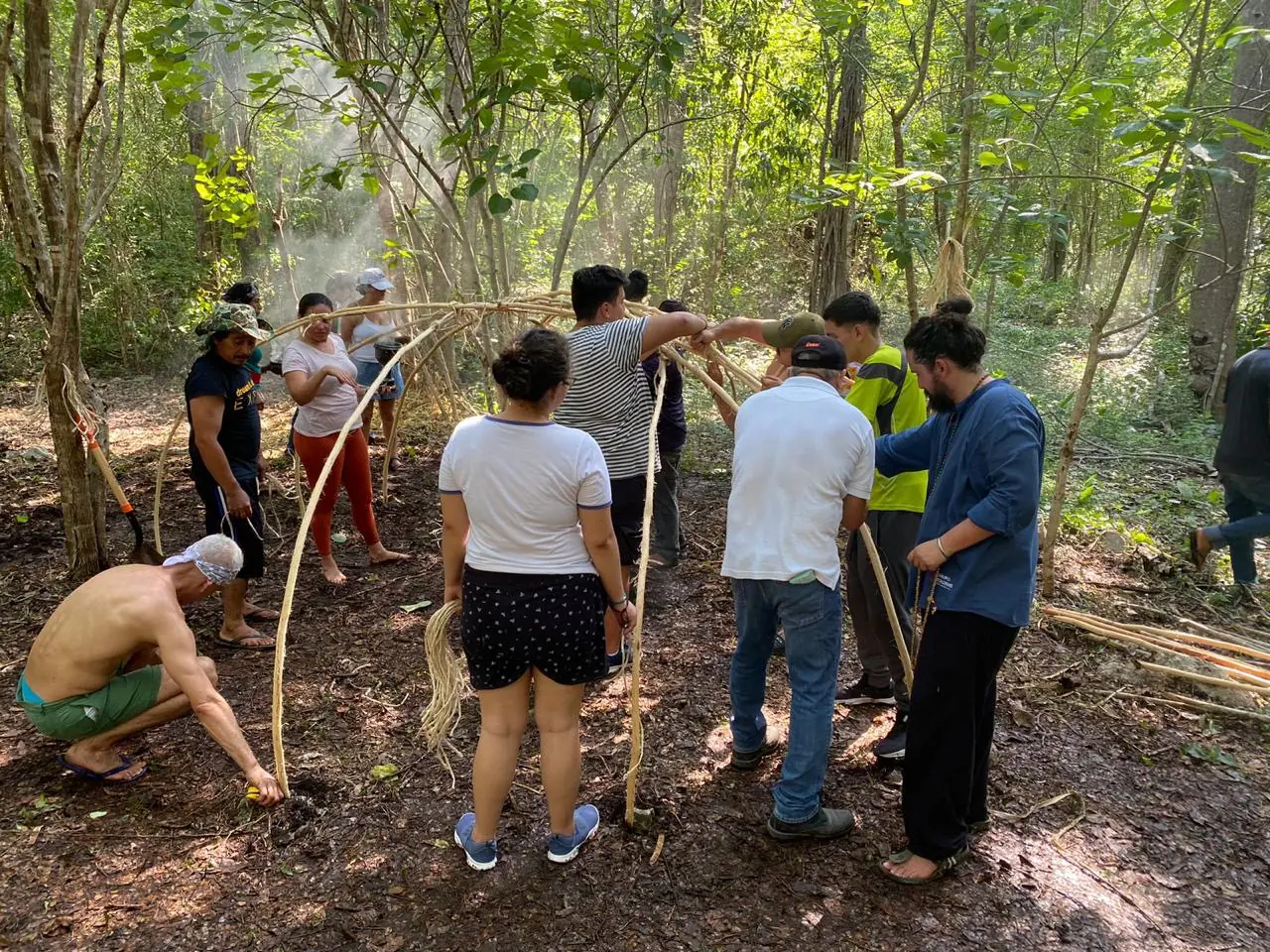 Varias personas levantando la estructura de varas del temazcal