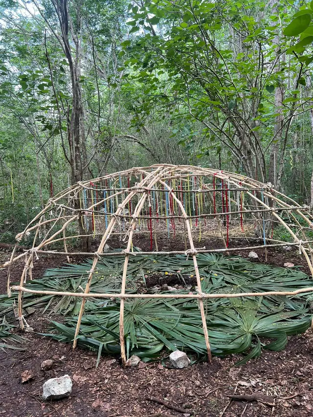 Domo de varas de un temazcal recién levantado, con los listones de los siete chakras colgando adentro